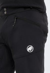 Μαύρο παντελόνι με φερμουάρ σε πλαϊνή τσέπη, δύο μεταλλικά κουμπιά στη μέση και λευκό λογότυπο μαμούθ στον μηρό.