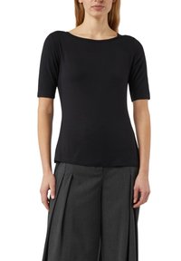 Czarny krótki top z miękkiej tkaniny z dekoltem w łódkę, charakteryzujący się gładką fakturą i dopasowanym krojem, zestawiony z plisowanymi szarymi spodniami.