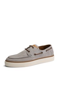 Zapato de ante gris con acentos texturizados, ojales marrones y una suela de goma blanca contrastante. Diseño clásico de zapato náutico con detalles de costura.