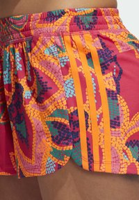 Pantalones cortos de atletismo coloridos con un vibrante patrón de rosa, naranja y verde. Incluye franjas naranjas y un detalle del logo de Adidas.