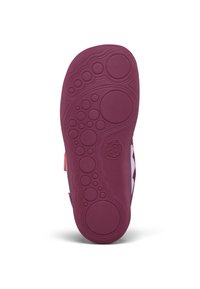 Semelle de chaussure en caoutchouc violet présentant un motif circulaire et texturé, avec des zones surélevées créant de l'adhérence, et un petit logo embossé sur le côté.