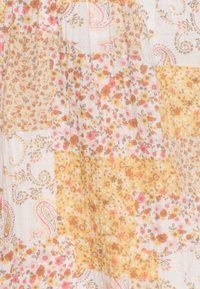 Tessuto floreale e a motivo paisley in tonalità di giallo tenue, rosa e marrone, con una finitura morbida e testurizzata e un design a patchwork.