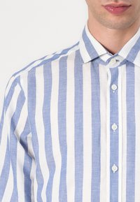 Camicia in lino a righe blu e bianche con colletto button-down, dotata di bottoni piccoli e finitura in tessuto testurizzato.
