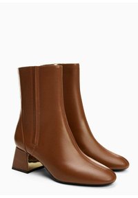 Ruskeat nahkaiset nilkkurit, joissa on terävä kärki ja matala blokkikorko. Niissä on sileä pinta ja metallinen yksityiskohta korossa.