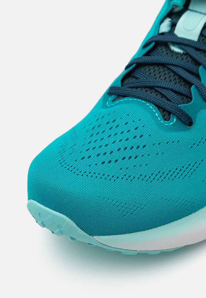 Scarpa sportiva turchese con tomaia in mesh traspirante, motivo testurizzato e lacci scuri. Suola arrotondata con accenti di teal chiaro.