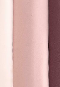 Drie verticale stofrollen in tinten wit, lichtroze en donker mauve nauw naast elkaar uitgelijnd.
