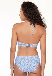 Niebieski bikini w wzory z halterem i regulowanymi zapięciami. Ozdobione motywem kwiatowym oraz zapięciem na plecach. Miękka, strukturalna tkanina.