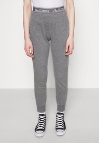 Grå sweatpants med ribbad midja som har en logotyp. Taperad ben-design och elastiska muddar. Matchas med svarta och vita sneakers.