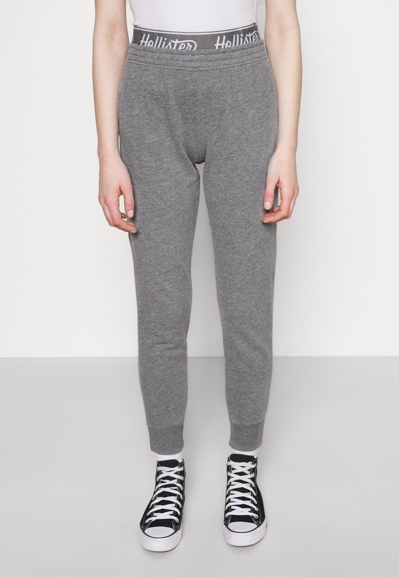 Grå sweatpants med ribbad midja som har en logotyp. Taperad ben-design och elastiska muddar. Matchas med svarta och vita sneakers.