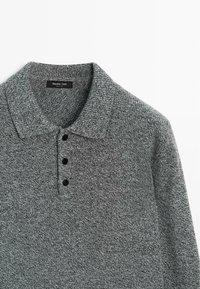 Koszulka polo z ciemnoszarej dzianiny, z klasycznym kołnierzykiem, trzema czarnymi guzikami oraz fakturowaną powierzchnią i lekką elastycznością.