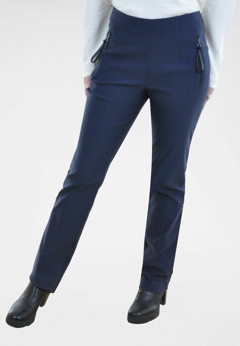 Navyblauwe skinny pantalons met ritszakken en zwarte hardware-accenten. Gladde stof, recht gesneden ontwerp, gecombineerd met zwarte haklaarzen.