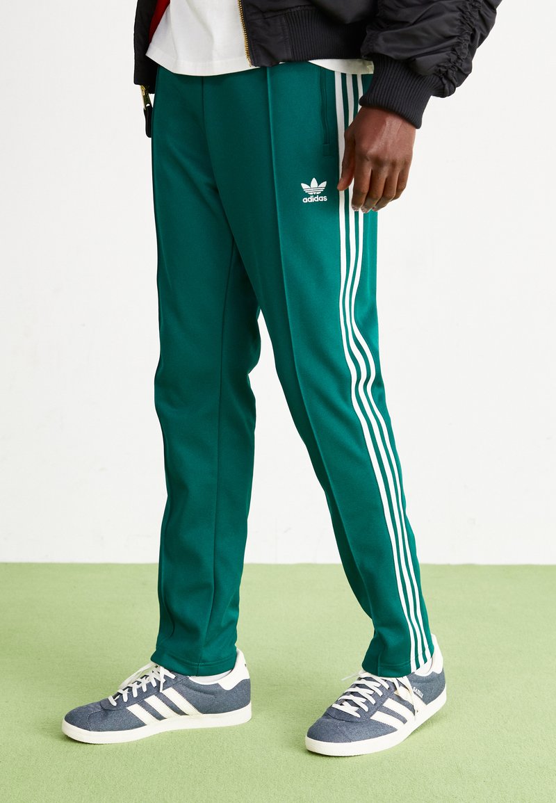 Grønne sportbukser med hvide tre-stribe accenter og Adidas-logo. Fremstillet af blødt stof, med en lige ben-design og elastisk talje. 