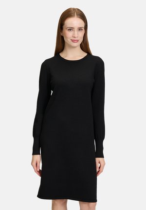 Abito nero lavorato a maglia con maniche lunghe, scollo rotondo e silhouette dritta. Tessuto morbido e lunghezza sopra il ginocchio. Design semplice.