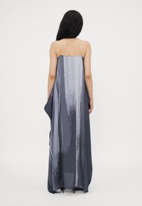 Lange grijze jurk met een gladde, zijdezachte textuur. Heeft een gradient ontwerp met lichtere en donkere tinten, en dunne, transparante bandjes.