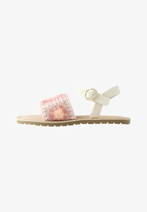 Flache Sandale mit einem rosa und beige gehäkelten Vorderriemen und einem beigen Knöchelriemen mit goldener Schnalle.