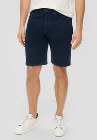 Granatowe szorty dżinsowe o prostym kroju, pięć kieszeni i szlufki na pasek. W połączeniu z białymi sneakersami z czarnymi akcentami.