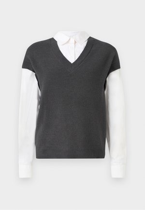 Mörkgrå stickad tröja med V-hals, med korta ärmar över en vit skjortkrage. Texturen är ribbad, med en lagerlook.