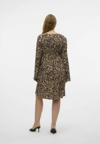 Abito a stampa leopardata con maniche lunghe e vita cintrata. Realizzato in un tessuto leggero, presenta una vestibilità comoda e un taglio al ginocchio.