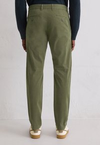 Zielone oliwkowe spodnie chino o prostym kroju nogawki, wykonane z miękkiej tkaniny. Posiadają dwie tylne kieszenie i dyskretne detale z metalu.