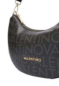 Borsa a tracolla in pelle nera con motivo a logo in rilievo "VALENTINO", hardware dorato e forma curva. Caratterizzata da chiusura con zip e tracolla regolabile.