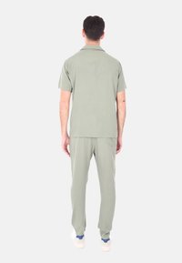 Completo di camicia a maniche corte verde chiaro e pantaloni abbinati, realizzato in tessuto morbido con una vestibilità comoda e dettagli di cucitura semplici.