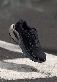 Nike-Laufschuh mit einem dunkelblauen Obermaterial und gesprenkelten Akzenten, schwarzem Swoosh-Logo und hellblauer Sohle. Atmungsaktives Mesh-Design.