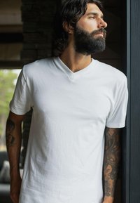 Hvid v-hals t-shirt lavet af blød bomuld, med korte ærmer og en afslappet pasform. Stoffet har en glat overflade og minimal rynkning.