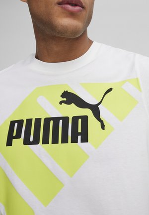 Biała koszulka z czarnym logo "PUMA" oraz sylwetką skaczącego kota, ozdobiona jasn yellowymi geometrycznymi akcentami. Krótkie rękawy i okrągły dekolt.