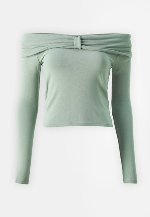 Váll nélküli, hosszú ujjú felső világos zöld színben, összehúzott nyakkivágással és testhezálló, rövid fazonnal. Puha textúra, rugalmasságot biztosító anyag.