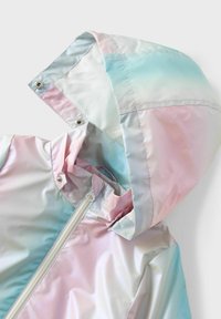 Veste de pluie légère irisée avec des dégradés pastel rose, bleu et blanc. Dispose d'une capuche, de poches latérales et d'une fermeture éclair frontale.