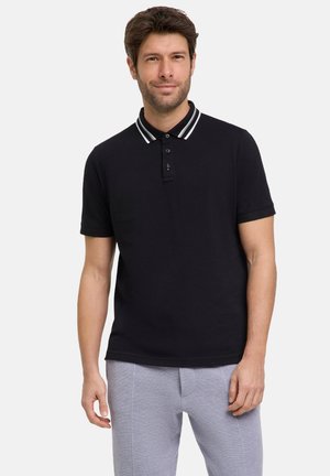 Zwart poloshirt met een knoopsluiting met twee knopen, kraag met witte en groene strepen en korte mouwen. Het model draagt een grijze broek.