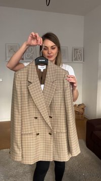 Dvojřadý blazer v béžovém a hnědém kostkovaném vzoru, s klopovým límcem, předními kapsami a zlatými knoflíky.