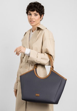 Sac fourre-tout bleu marine avec des poignées et des bordures en simili cuir marron. Design lisse et structuré avec un patch logo à l'avant.