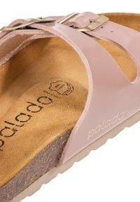 Sandal in patent rosa con suola in sughero, caratterizzata da ritagli, una soletta testurizzata e una fibbia in metallo dorato. Logo "palado" impresso sulla soletta.