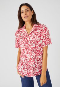 Camicia a maniche corte con bottoni, caratterizzata da un motivo floreale rosso e bianco su tessuto leggero. Vestibilità rilassata con colletto classico.