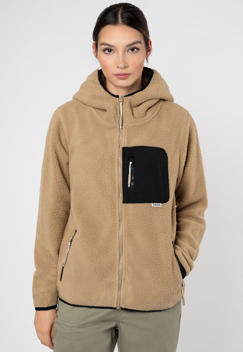 Beige Fleece-Hoodie mit einer schwarzen Reißverschlusstasche auf der Brust. Verfügt über eine weiche Textur, einen vollen Reißverschluss vorne und eine verstellbare Kapuze.