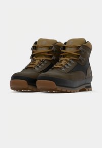 Pruunid ja mustad matkajalanõud, millel on tekstureeritud ülemine osa, paelad, paks kummist tald ja metallist silmad, ning pehmendusega krae.