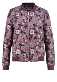 Kwiatowa kurtka bomberka w fioletowym materiale, z zamkiem z przodu, ściągaczami przy mankietach i u dołu, z różowymi i złotymi akcentami w kwiatowym wzorze.