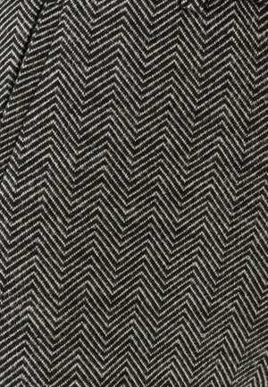 Tissu avec un motif zigzag noir et blanc, présentant un design texturé et tissé. Le tissu affiche un style chevrons.