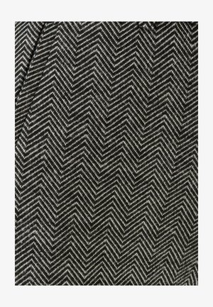 Tessuto con un motivo a zigzag bianco e nero, caratterizzato da un design tessuto e testurizzato. Il materiale presenta uno stile a spina di pesce.