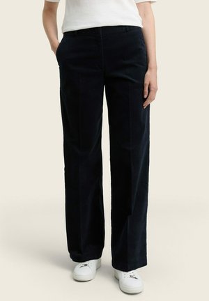 Navy wide-leg corduroy pants with two side pockets, featuring a smooth texture, belt loops, and front creases. Worn with white sneakers.