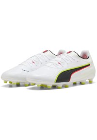 Valkoiset Puma-jalkapallokengät mustilla, punaisilla ja keltaisilla yksityiskohdilla, nauhoilla ja nastapohjilla, jotka tarjoavat pitoa nurmipinnoilla.