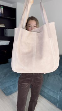 Borsa tote in suede rosa chiaro con due manici lunghi, caratterizzata da una texture liscia e un design semplice, non decorato.