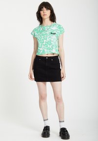 Groen en wit patroon cropped t-shirt, zwarte denim mini rok met rafelige zoom, zwarte platform schoenen en witte sokken met zwarte strepen.