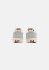 Szare zamszowe i gładkie materiałowe sneakersy z białą gumową podeszwą i czerwonym logo "Vans" na pięcie. Niskoprofilowy design z zaokrąglonym tyłem.