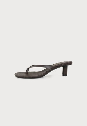 Sandale marron à talon avec semelle texturée et fine bride unique, sur fond blanc uni.