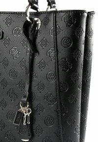 Zwarte draagtas van imitatieleder met geperste decoratieve patronen, zilveren metalen accenten en een afneembare sleutelhanger met "GUESS"-label.