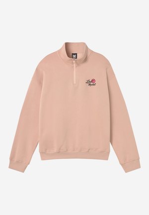 Ανοιχτό ροζ πουλόβερ με μακριά μανίκια, γιακά με φερμουάρ κατά το ένα τέταρτο της διαδρομής και μικρό κείμενο "Lost Motel" με ροζ κύκλο λογότυπο στο αριστερό μέρος του στήθους.