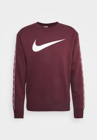 Maroon sweatshirt with long sleeves, ribbed cuffs, and a white Nike swoosh logo on the front. White and burgundy patterned accents on sleeves.