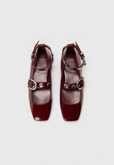 Burgundy patent leather shoes with square toes, adjustable ankle straps, silver-tone buckles, and a smooth, textured interior.